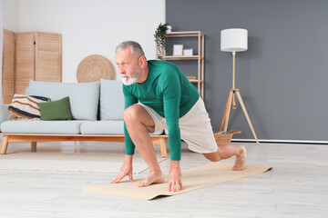 Wall Mural - Sporty mature man practicing yoga at home