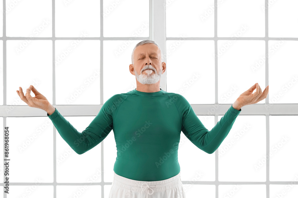 Sporty mature man meditating in gym