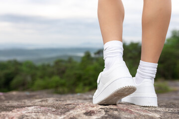 athletic legs in white sneakers and white socks close-up. athlete. traveler on a rock in white sneak