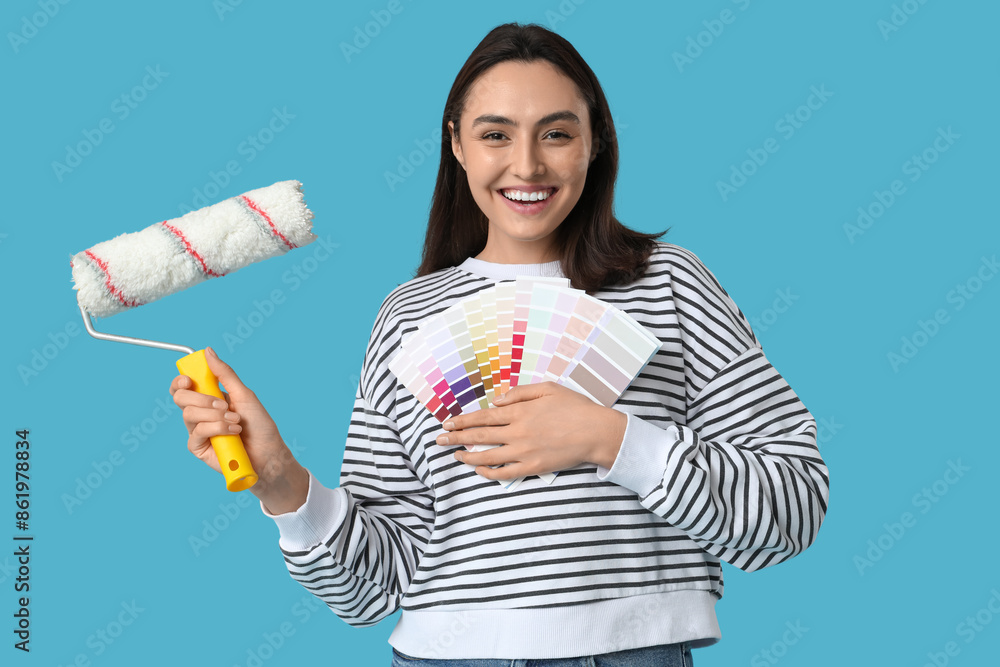 Young woman with paint roller and color palettes on blue background