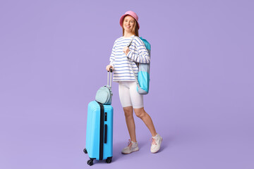 Sticker - Smiling young woman with her luggage on lilac background. Travel concept