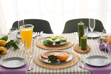 Wall Mural - Beautiful table setting with citrus fruits, candles and juice on checkered tablecloth in living room