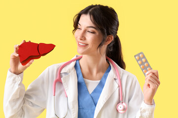 Wall Mural - Female doctor with paper liver and pills on yellow background, closeup