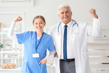 Wall Mural - Mature doctor with nurse showing muscles in clinic