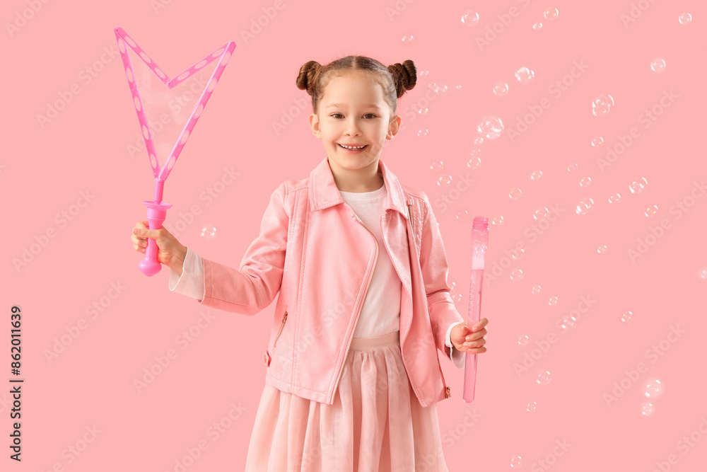 Cute little girl with soap bubbles on pink background