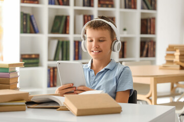 Wall Mural - Teenage boy in headphones with tablet computer at library