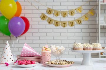 Wall Mural - Table with different sweets and decor for birthday party against white brick wall