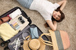 © New Africa - Woman packing suitcase for trip on floor indoors, top view
