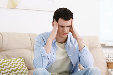 Canvas Print - Man suffering from headache on sofa at home