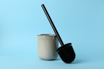 Toilet brush and holder on light blue background