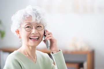 Wall Mural - close-up of an elderly (senior) woman holding a cell phone (cell phone) and talking, looking at the 
