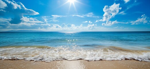 A serene beach scene with clear blue waters, white frothy waves, and a pristine sandy shore under a brilliant blue sky with scattered white clouds and the sun shining brightly.