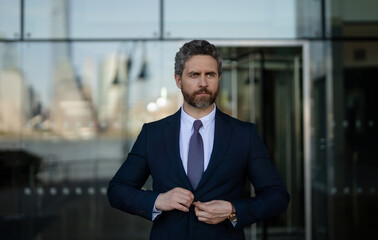 Confident business man standing outdoor on modern office building. Business success. Business man thinking outdoor. Modern businessman in full suit standing outdoors near office cityscape.