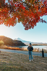 Wall Mural - Woman tourist with Fuji Mountain at Lake Kawaguchi in Autumn season, happy Traveler travel Mount Fuji, Yamanashi, Japan. Landmark for tourists attraction. Japan Travel, Destination and Vacation