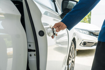 a businessman stands next to his damaged vehicle after an accident, holding a clipboard and examinin