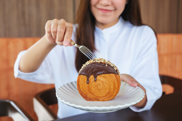 Wall Mural - Closeup image of a woman eating a chocolate Timber Ring croissant with fork