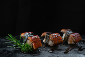 close up, unagi eel nigiri sushi (eel sushi), japanese style food, is arranged on a black stone plat