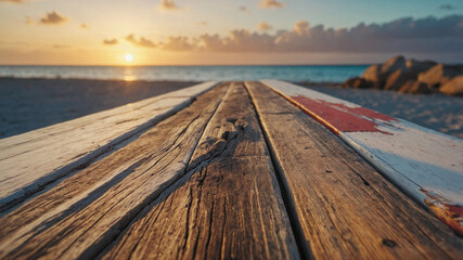 Wall Mural - A wooden bench on a beach with the sun setting in the background