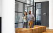 © Wavebreak Media - Business colleagues walking in office, holding coffee and tablet, discussing work
