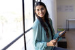 © Wavebreak Media - Smiling businesswoman holding tablet and looking out window in modern office