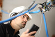 © Antonioguillem - Electrician checking electrical installation using phone