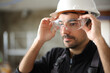 © Antonioguillem - Construction worker putting protective glasses before work