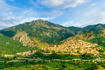 amazing mountain landscape with old yellow italian town among green beatiful mountains and cloudy sky above