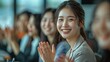 © Surachetsh - A group of Asian business professionals, smiling and clapping their hands, is attending a work conference and listening to presentations. People have seats in the auditorium or meeting room.