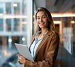 © Yummy Yoo - Portrait of happy businesswoman with touchpad in office looking at camera