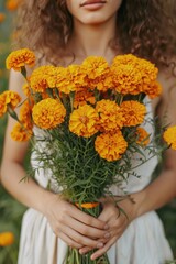 Canvas Print - close-up of a woman holding marigold flowers in her hands. Selective focus