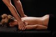 © st.kolesnikov - handsome male masseur giving massage to girl on black background, therapeutic relaxing massage