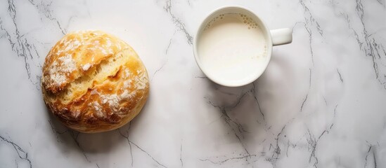 Poster - Top view image showcasing a white round bread placed alongside a mug of milk on a marble surface, with ample copy space available.