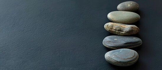 Wall Mural - Sea stones arranged in a minimalistic style on a black background with copy space image.