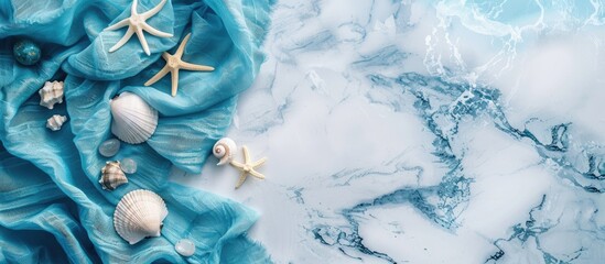 Leinwandbilder - White marble surface decorated with blue fabric, stones, and seashells against a backdrop of the sea, with copy space image.