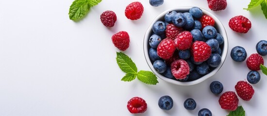 Wall Mural - Cookie cutter filled with blueberries and raspberries on a white background with mint leaves nearby - fresh berries in a cookie form copy space image.