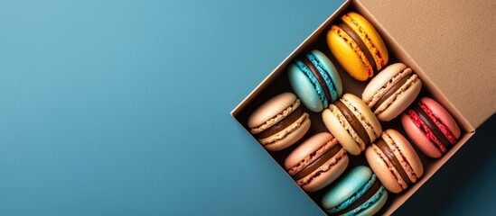 Poster - A cardboard box filled with vibrant macaron cookies against a copy space image.