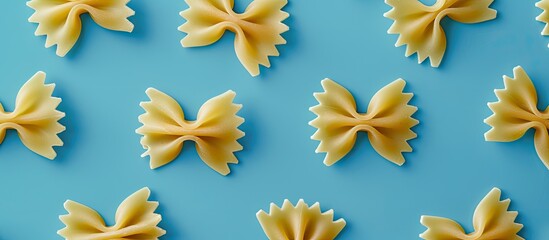 Wall Mural - Top view of uncooked bowtie pasta with room for text or other elements on a blue backdrop, showcasing this Italian culinary staple. Copy space image. Place for adding text and design