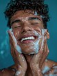 © vefimov - A man is washing his face with soap and water, smiling as he does so. Concept of relaxation and self-care, as the man takes the time to cleanse his face and enjoy the process