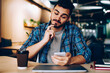 © BullRun - Contemplative male analyzing information about booking on website using cellular in coworking space,puzzled hipster guy pondering on getting receipt for payment checking email via smartphone