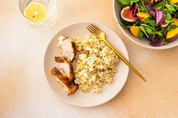 Delicious hearty lunch, brown rice with baked chicken breast and seeds, mixed salad with figs and peach