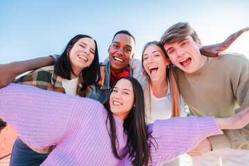 Fototapete - Group of real multiracial teenagers having fun together and posing for a portrait. Young friends smiling and laughing. Multiethnic people bonding outside with positive and friendly expression