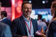 © Surachetsh - A smiling businessman engages in friendly banter with software developers and tech industry leaders at a digital innovation conference, exuding fostering genuine connections.