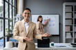 © Wasana - A man in a suit stands in front of a white board with a woman behind him