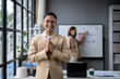 © Wasana - A man in a suit is standing in front of a white board with a woman behind him