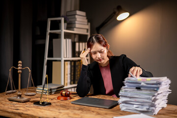 Wall Mural - A woman is sitting at a desk with stacks of papers and a laptop