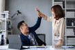 © Wasana - A man and a woman are high fiving each other in a cubicle