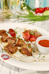 Wall Mural - Delicious Grilled Pork Shashlik with Lavash, Sauce, and Fresh Vegetable Salad in a Sunlit Outdoor Setting