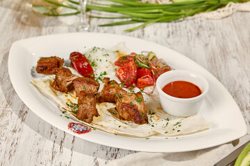 Wall Mural - Juicy Pork Skewers with Lavash, Sauce, and Fresh Vegetable Salad in Sunlight