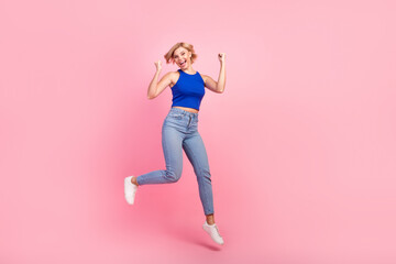 Wall Mural - Full body portrait of nice girl raise fists rejoice jump empty space wear blue top isolated on pink color background