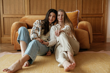 Front view, sitting. Two happy young female best friends are indoors